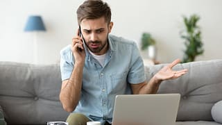 man on couch on phone call near laptop gfF.width .jpg