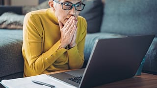 mature woman looking at computer in shock