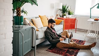 person on living room floor with laptop LRGGF.width .jpg