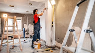 person putting up drywall in home renovation .width