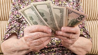 senior woman holding cash money bills social security cola retirement getty