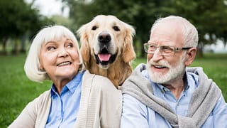 smiling senior couple looking at adorable dog