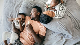two parents with young kids on bed HxMda.width .jpg