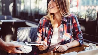 woman in restaurant paying with smart phone a.width