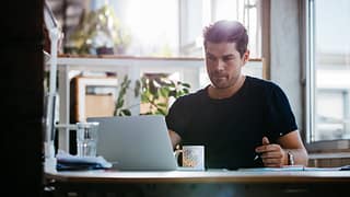 young man sitting at desk using laptop and th.width RMgeB