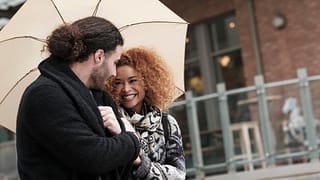 Couple walking through city under umbrella Ab.width .jpg