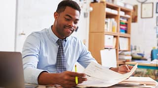 Man reading paperwork at desk UyTBhM.width .jpg