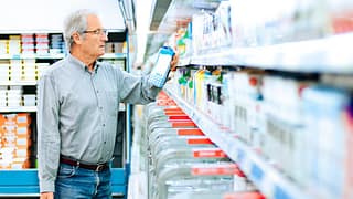 Mature man reads the label on a milk carton i.width .jpg