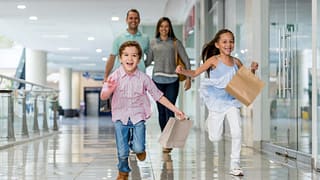 Parents and kids at shopping mall with shoppi.width GYqrug.jpg