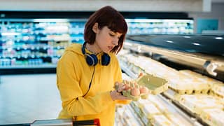 Shopper inspecting a carton of eggs in the gr.width .jpg