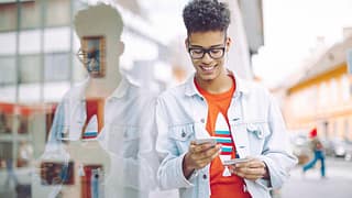 Teen boy using his phone and holding a credit.width .jpg