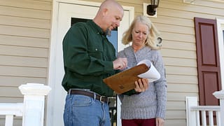 Woman on porch talking to man with clipboard .width .jpg