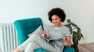 Woman reading magazine in a chair. XUgBQV.width .jpg