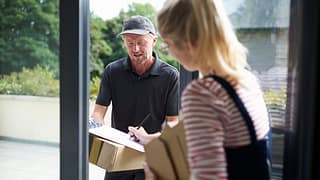 Woman signing for packages with a delivery pe.width VWyGgX.jpg