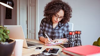 Woman taking notes while using a laptop IpOrU.width .jpg