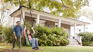 dad pushing daughter in swing in front yard.width .jpg