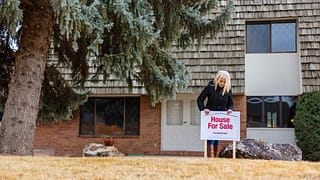 person in front of house with for sale sign S.width .jpg