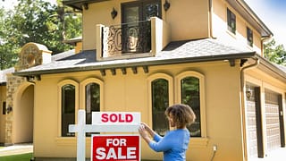 person putting sold sign in front of house T.width .jpg