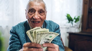 senior man counting cash money bills social security retire invest inflation cola getty.jpg