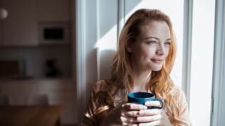smiling person sitting in window holding coffee mug.jpg