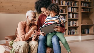 two adults and a child looking at a tablet and smiling.jpg