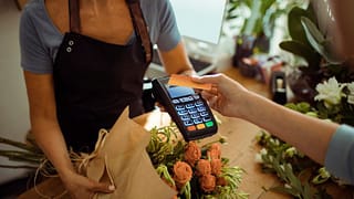 woman holding credit card over payment reader.width IAlpwc.jpg