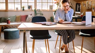 woman writing in notebook at desk near laptop.width OXuOD.jpg