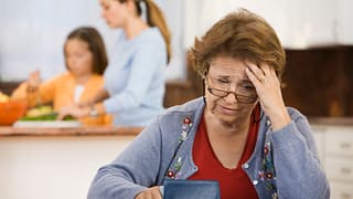 worried senior woman holding checkbook.jpg