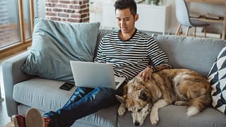young man on laptop on couch with dog QRysiD.width .jpg
