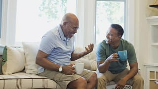 Cheerful father and son having coffee on sofa.width .jpg