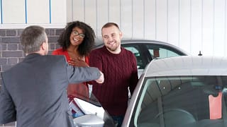 Couple shakes hand with a car salesman near a.width DnSBi.jpg