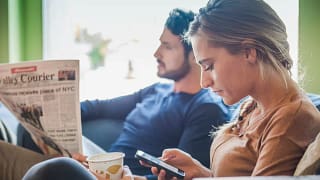 Couple sits together while one reads a newspa.width HSHgLW.jpg
