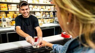 Employee handing sample of cheese to woman sh.width QAGKAOI.jpg
