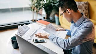 MAn using a calculator and looking over docum.width bFwUjX.jpg