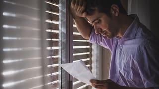 Man looks saddened by paper that hes reading .width .jpg