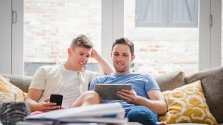 Young couple sit on sofa and look at tablet .width .jpg