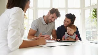 couple with baby signing house closing docume.width .jpg