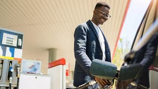 person filing up their car with gas AhVsk.width .jpg