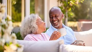two older people sitting outside drinking coffee and smiling.jpg