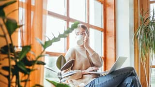 woman with coffee and laptop looking out wind.width .jpg