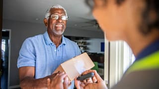 Man accepting package from a delivery driver .width .jpg