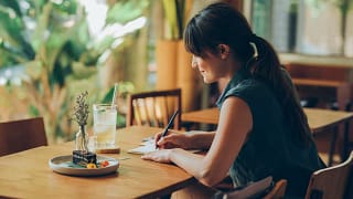 Woman writes letter at cafe table YKfcOac.width .jpg