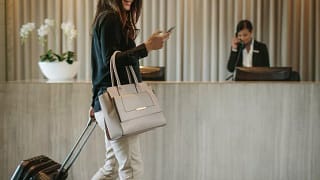 woman with suitcase and phone in hotel lobby.width .jpg