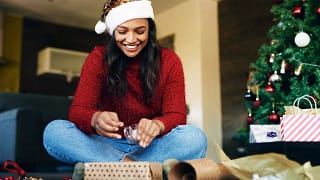 Woman wearing Santa hat wrapping gifts RKFz.width .jpg