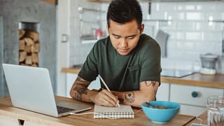 man at table writing in notebook NHASUaV.width .jpg