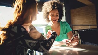 Friends looking at the mobile phone at a cafe.width qMyFab.jpg