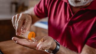 older man pouring pills into hand gettyimages .jpg