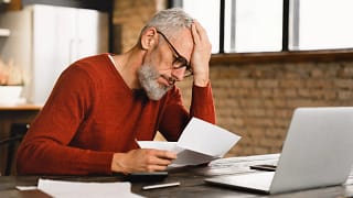 older man stressed holding document at laptop gettyimages .jpg