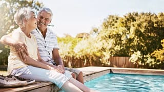 smiling seniors sitting by a pool.jpg