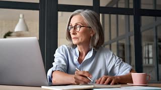 a person at a laptop holding a pen gettyimages .jpg